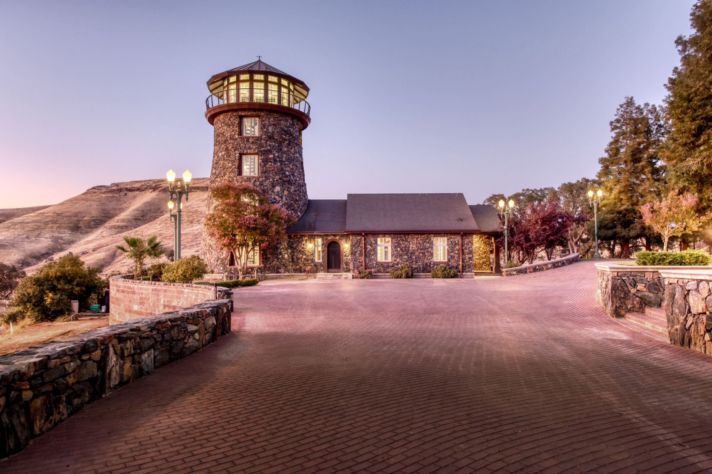 The estate at dusk, the granite lighthouse rising over the courtyard