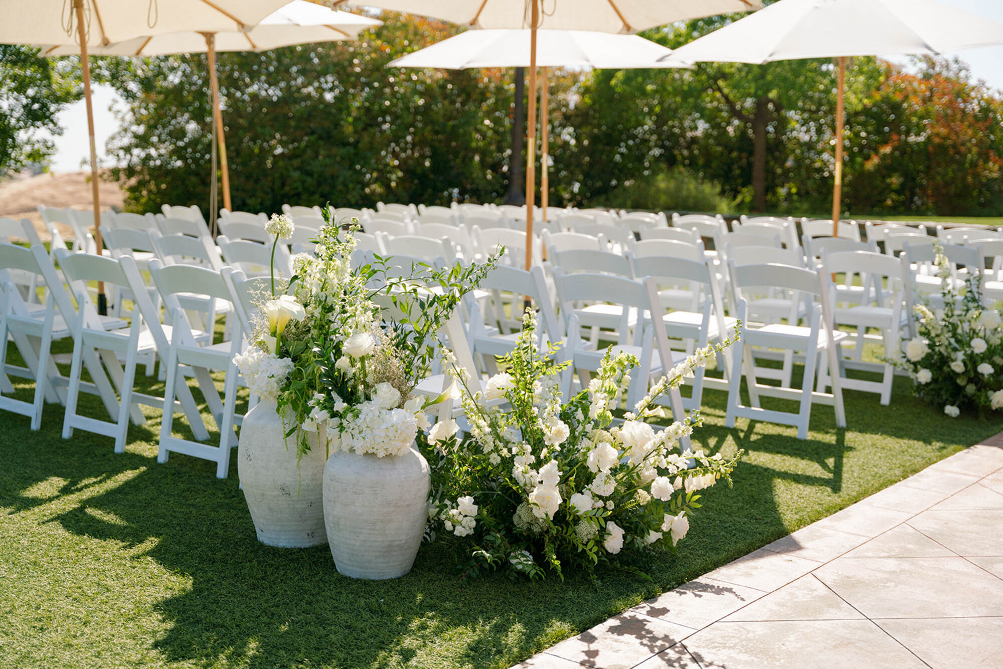 A ceremony aisle lined with white florals and rows of chairs on the estate lawn